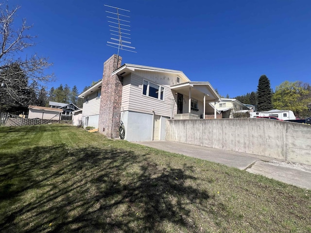 825 N Jefferson St, Colville, WA 99114 - view of side of property with a chimney, fence, a yard, concrete driveway, and an attached garage