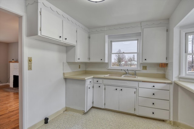 403 W Chestnut St, Almira, WA 99103 - kitchen with a sink, baseboards, white cabinets, light countertops, and a fireplace