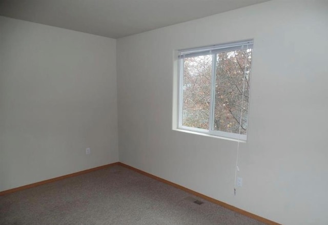 carpeted spare room featuring baseboards