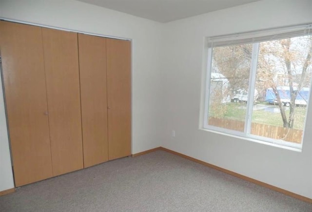 unfurnished bedroom featuring a closet, baseboards, and light carpet