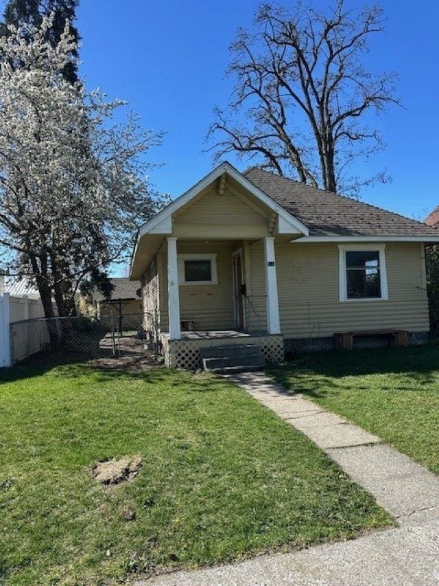 bungalow-style home with fence, a front yard, and covered porch