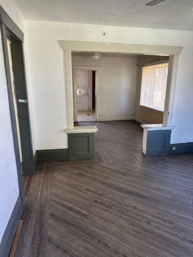 corridor with dark wood finished floors, a textured ceiling, and baseboards
