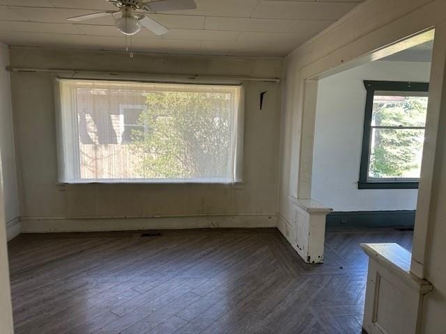 empty room with wood finished floors, a healthy amount of sunlight, and ceiling fan