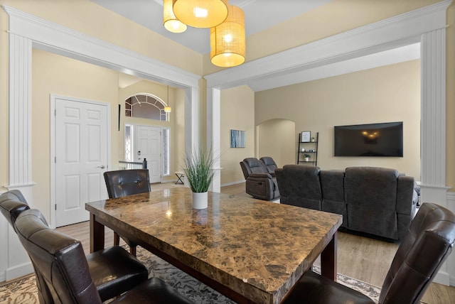 dining area with arched walkways, light wood finished floors, and ornate columns