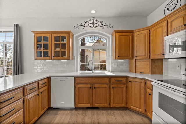 kitchen with decorative backsplash, a sink, white appliances, and light countertops