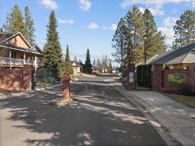 view of street featuring a gate, curbs, sidewalks, and street lights