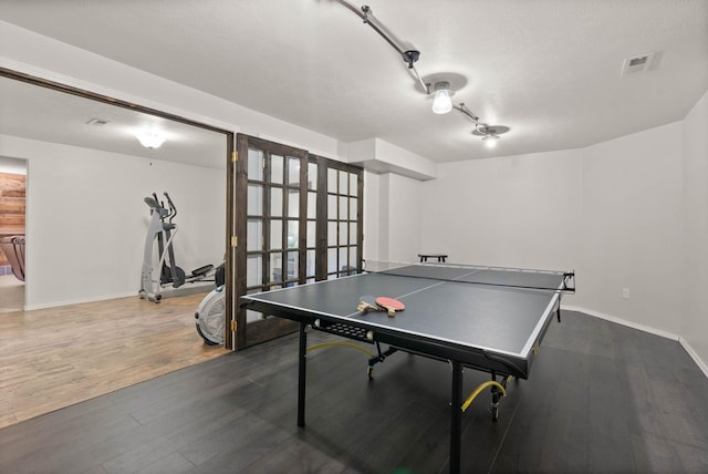 recreation room featuring baseboards, wood finished floors, and visible vents