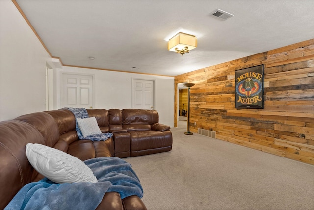 carpeted living area featuring wood walls, visible vents, and crown molding