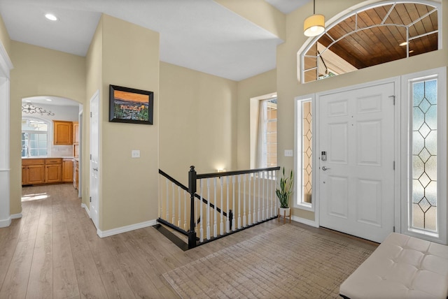 entryway with recessed lighting, arched walkways, light wood-style floors, and baseboards