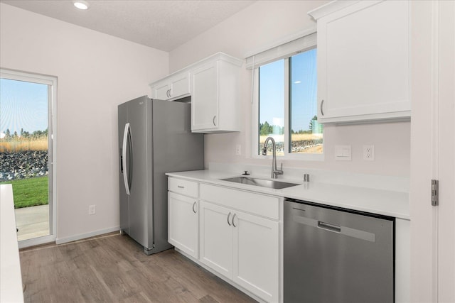 kitchen featuring a sink, light wood-style flooring, light countertops, white cabinets, and appliances with stainless steel finishes