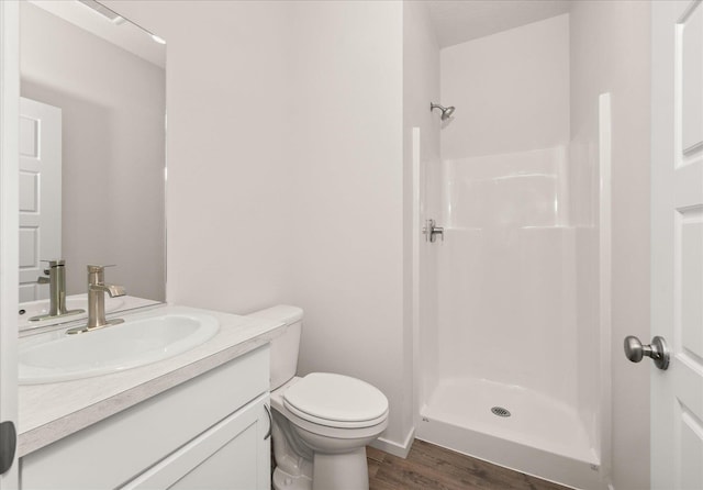 full bathroom featuring wood finished floors, vanity, toilet, and a stall shower