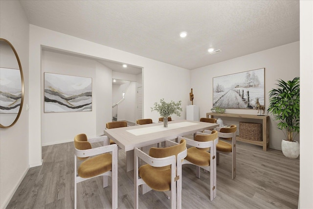 dining space featuring recessed lighting, light wood-style floors, a textured ceiling, and baseboards