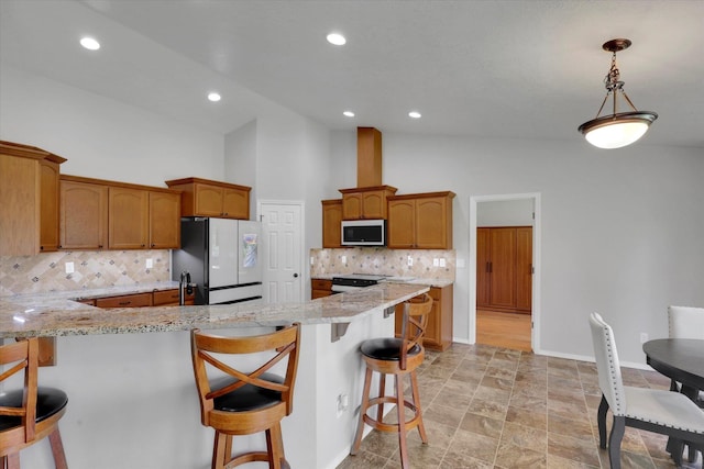 5818 S Abbott Rd, Spokane, WA 99224 - kitchen featuring white appliances, a kitchen bar, backsplash, brown cabinets, and a peninsula