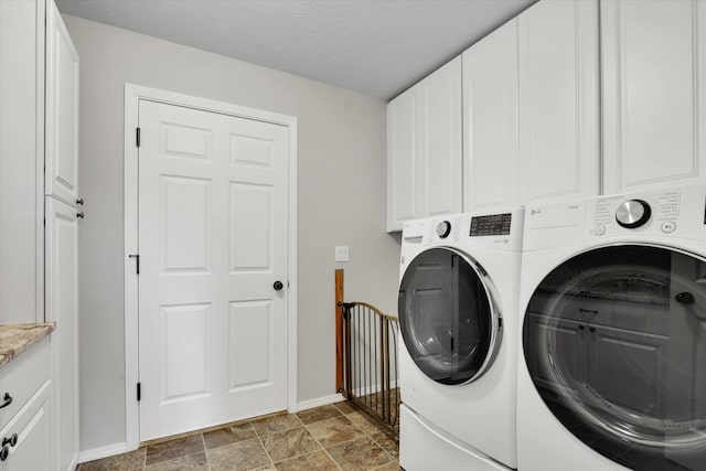 5818 S Abbott Rd, Spokane, WA 99224 - laundry area featuring washer and dryer, baseboards, cabinet space, and stone finish floors