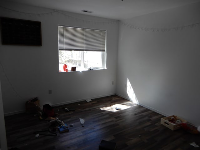 spare room featuring baseboards, wood finished floors, and visible vents