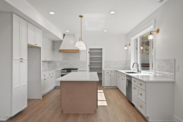 kitchen with light wood-style flooring, a sink, custom range hood, and tasteful backsplash