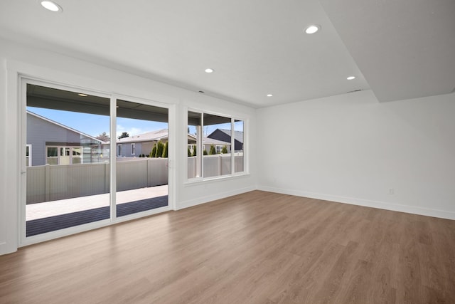 empty room with baseboards, wood finished floors, and recessed lighting