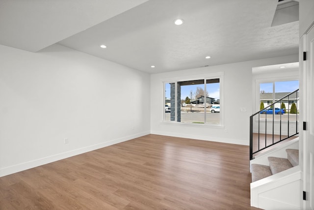 spare room with baseboards, stairs, wood finished floors, and recessed lighting