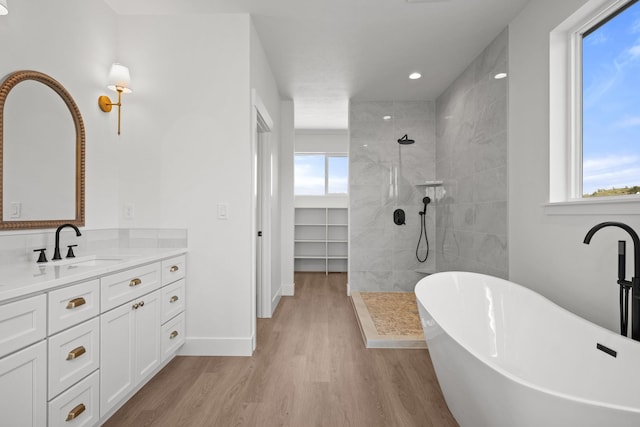 bathroom with wood finished floors, a wealth of natural light, a soaking tub, and a walk in shower