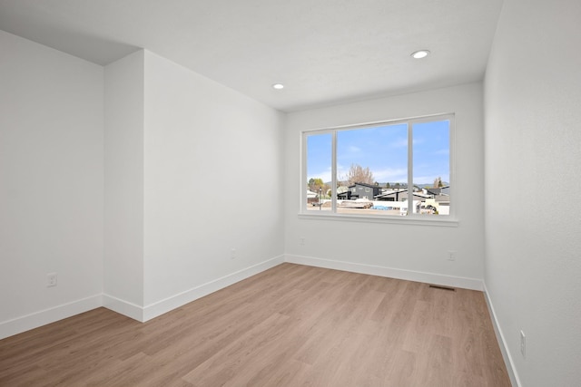 empty room featuring light wood-type flooring, baseboards, recessed lighting, and visible vents