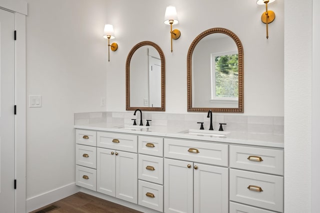 full bath featuring double vanity, visible vents, wood finished floors, and a sink