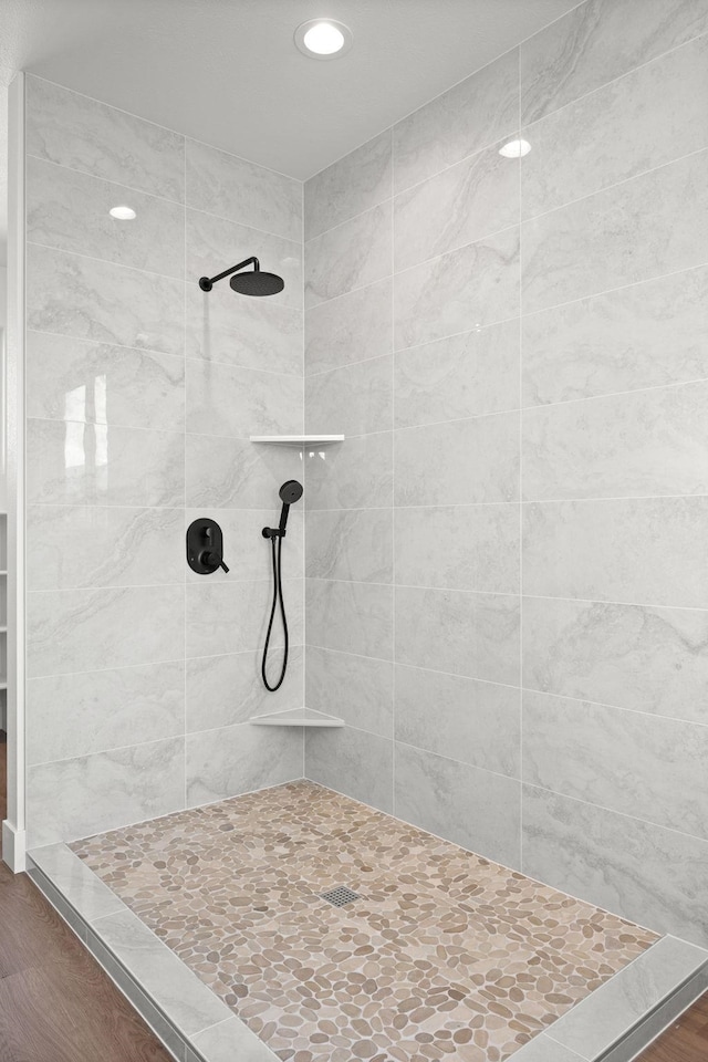 full bathroom featuring wood finished floors, recessed lighting, and tiled shower