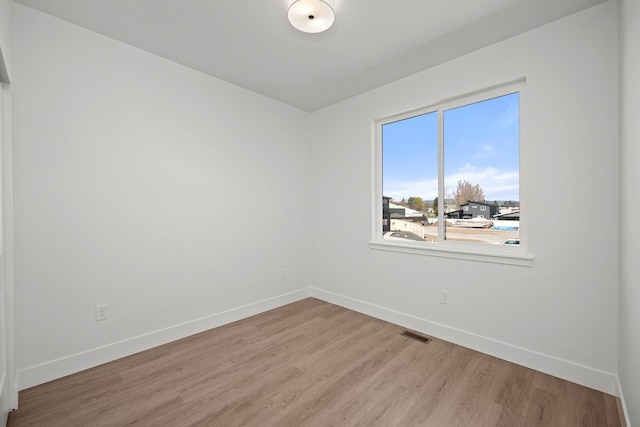 spare room featuring baseboards, visible vents, and light wood-type flooring