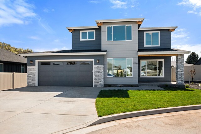 prairie-style home with driveway, stone siding, a front lawn, and fence