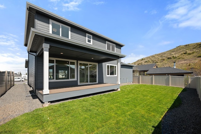 back of house with a deck with mountain view, a lawn, and a fenced backyard