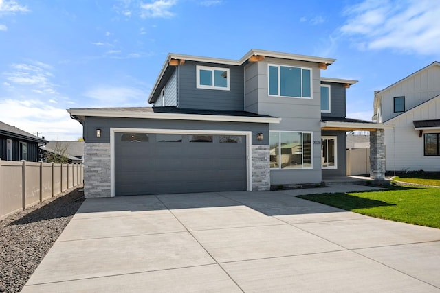 view of front of home with stone siding, an attached garage, fence, and concrete driveway