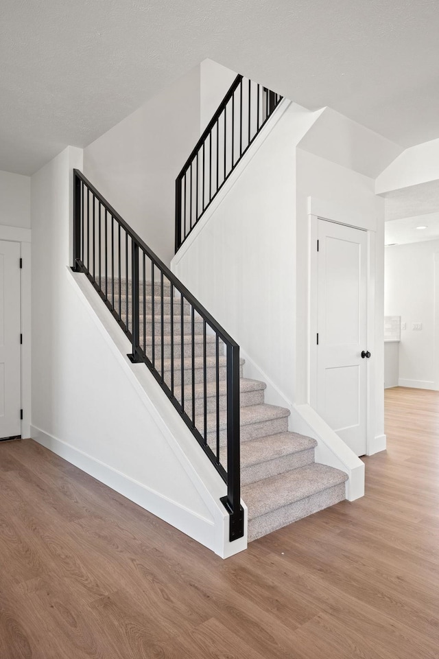 staircase with baseboards and wood finished floors