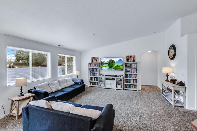 carpeted living room with arched walkways, lofted ceiling, visible vents, and baseboards