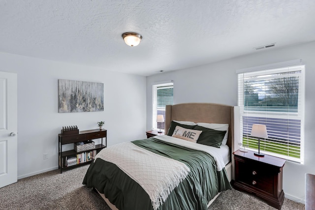 bedroom with a textured ceiling, carpet floors, visible vents, and baseboards