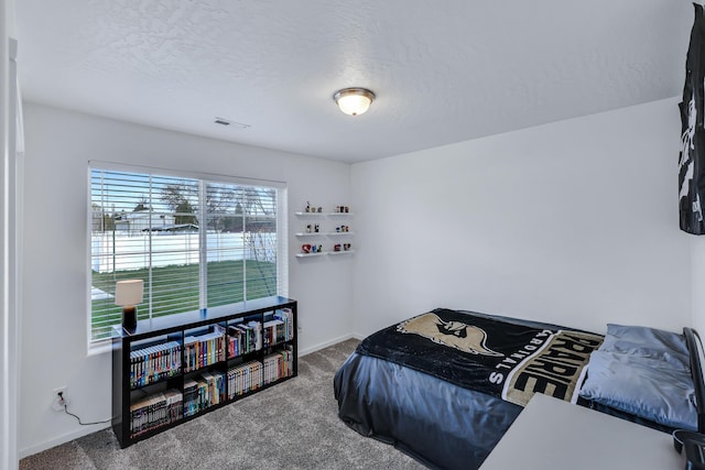 carpeted bedroom featuring baseboards, a textured ceiling, and visible vents
