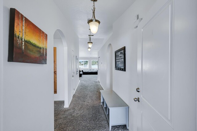 corridor featuring arched walkways, baseboards, and carpet