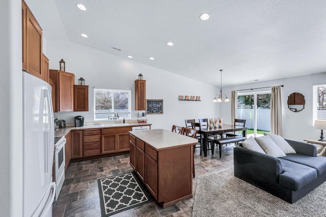 kitchen featuring stone tile floors, a center island, white appliances, and a sink