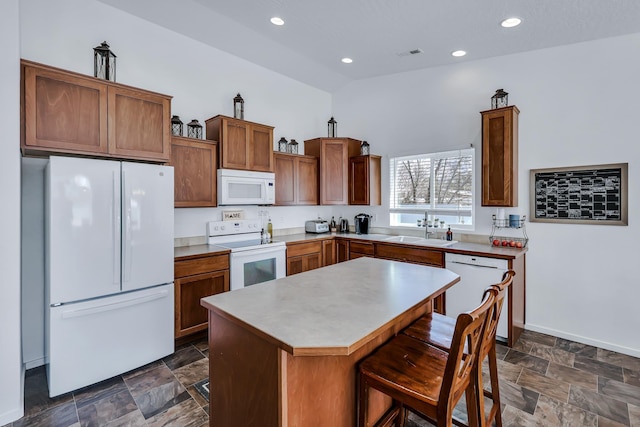 kitchen with a center island, a sink, visible vents, stone finish floor, and white appliances