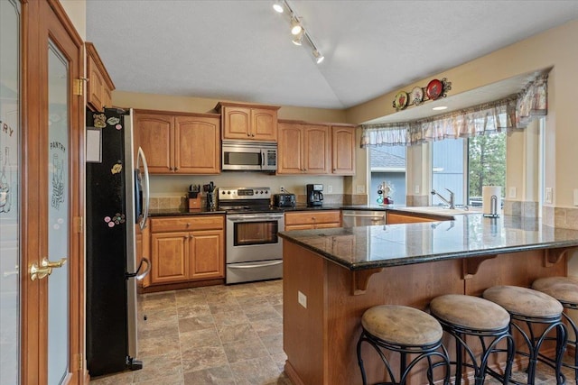 28 E Lindsey Ln, Spokane, WA 99208 - kitchen featuring stainless steel appliances, a peninsula, a kitchen bar, a sink, and vaulted ceiling