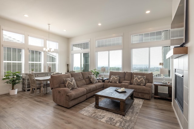 living area featuring plenty of natural light, a fireplace, wood finished floors, and an inviting chandelier