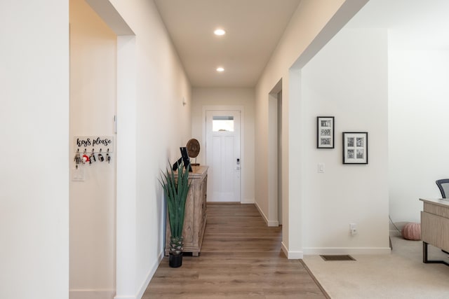 hallway featuring baseboards, light wood-style flooring, visible vents, and recessed lighting