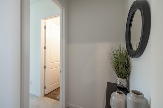 corridor with baseboards and light colored carpet