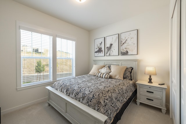 bedroom with baseboards, light colored carpet, and multiple windows