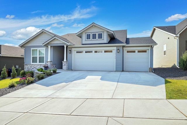 craftsman-style house with driveway, roof with shingles, and a garage
