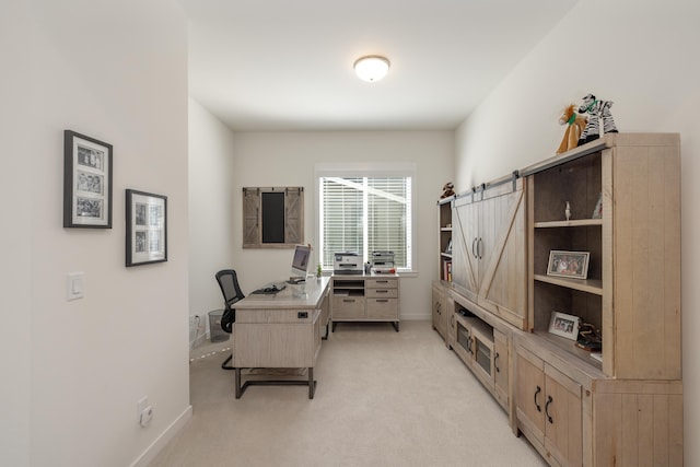 office space with light carpet, baseboards, and a barn door