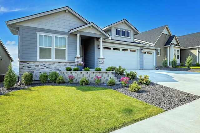 craftsman-style home with a garage, driveway, stone siding, and a front yard