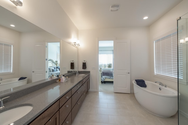 ensuite bathroom featuring double vanity, a freestanding tub, a sink, and connected bathroom
