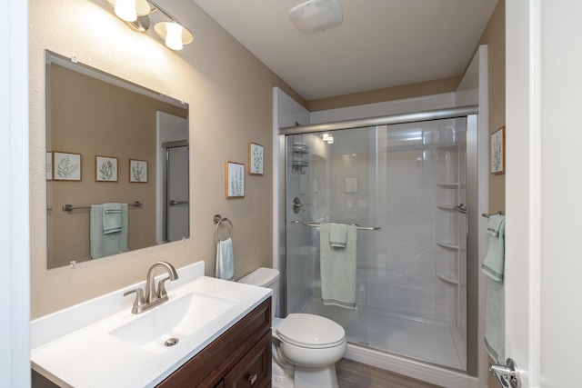 bathroom featuring toilet, vanity, and a stall shower