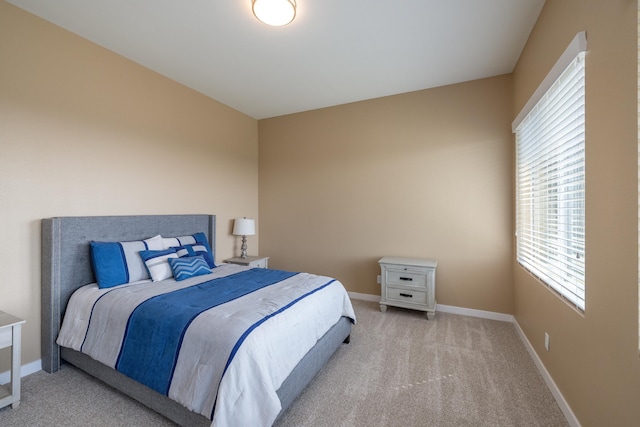 bedroom featuring multiple windows, baseboards, and light carpet