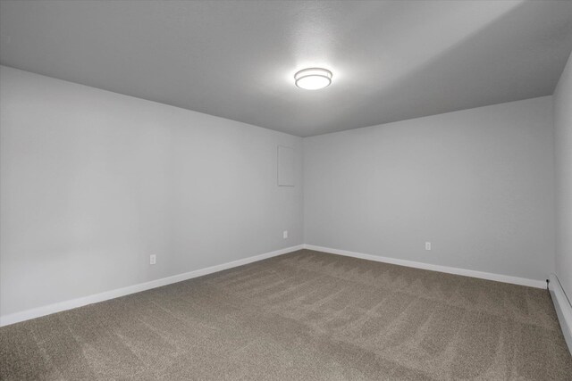 unfurnished room featuring dark carpet and baseboards