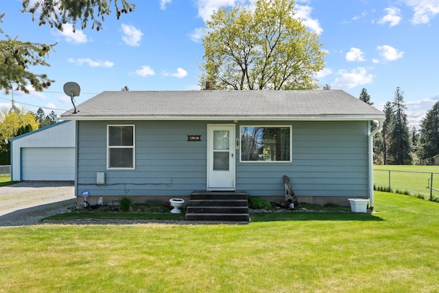 view of front of property with an outbuilding, a front lawn, a detached garage, fence, and entry steps